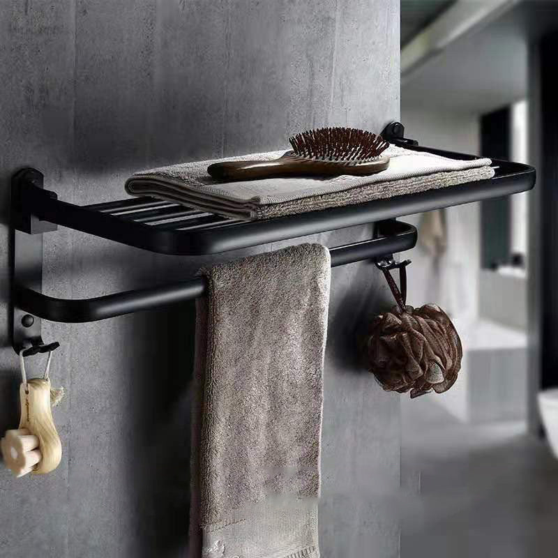 Perforated space aluminum bathroom folding shelf with hooks displaying towels and accessories.