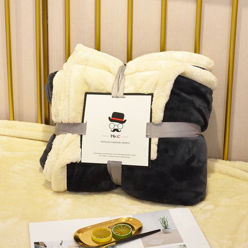 Thermal fluffy fleece blanket with black flannel and cream lamb fleece, displayed on a bed.