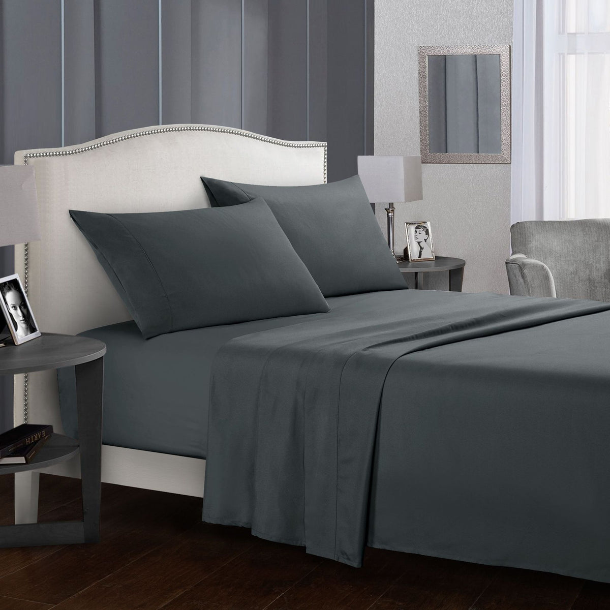 Four-piece bed sheet set in dark grey on a bed in a modern bedroom setting.