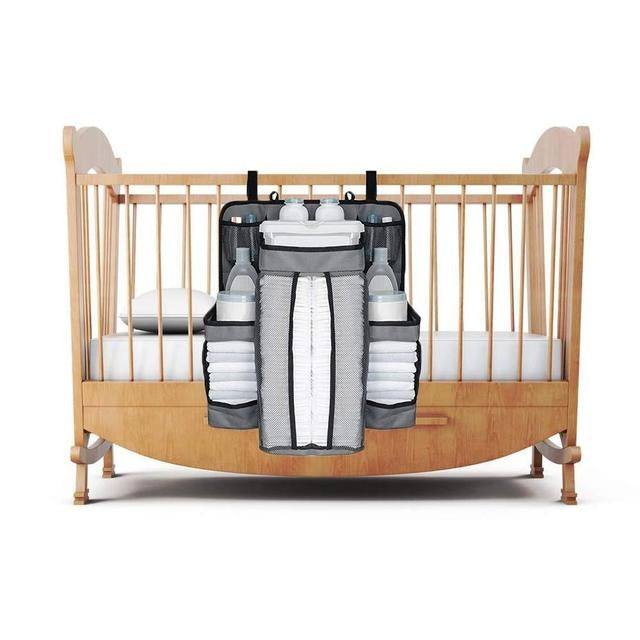 Crib storage bag attached to crib, holds diapers, bottles, and toys in large compartments.