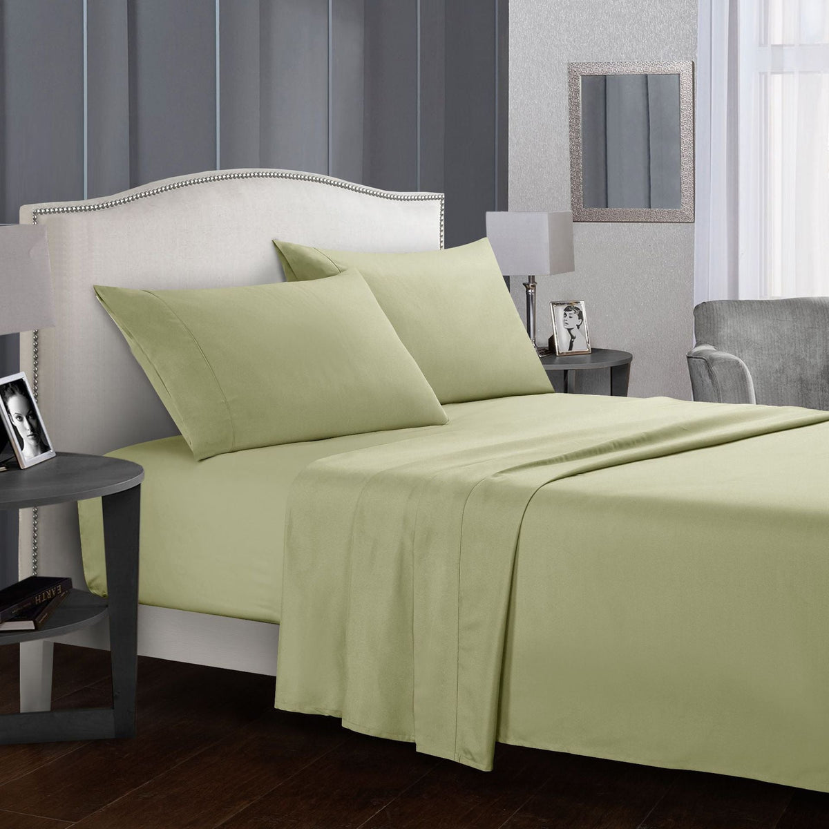 Four-piece bed sheet set in a modern bedroom setting with pillows and bedside table.