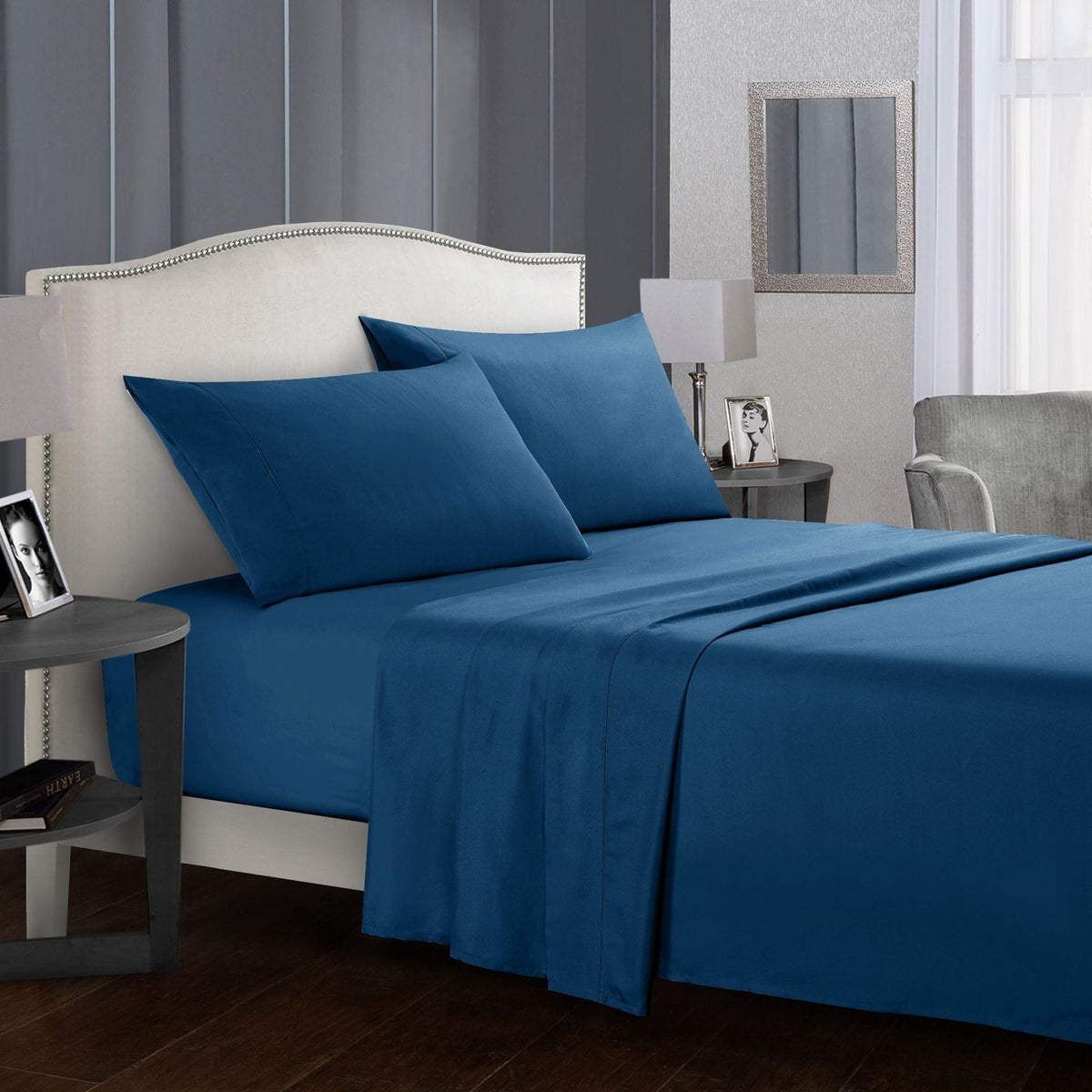Luxury blue four-piece bed sheet set on a made-up bed.