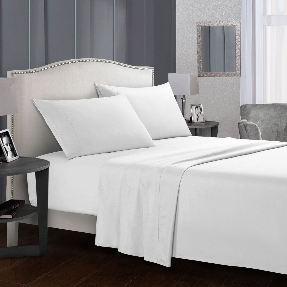 Four-piece white bed sheet set on a modern bed.