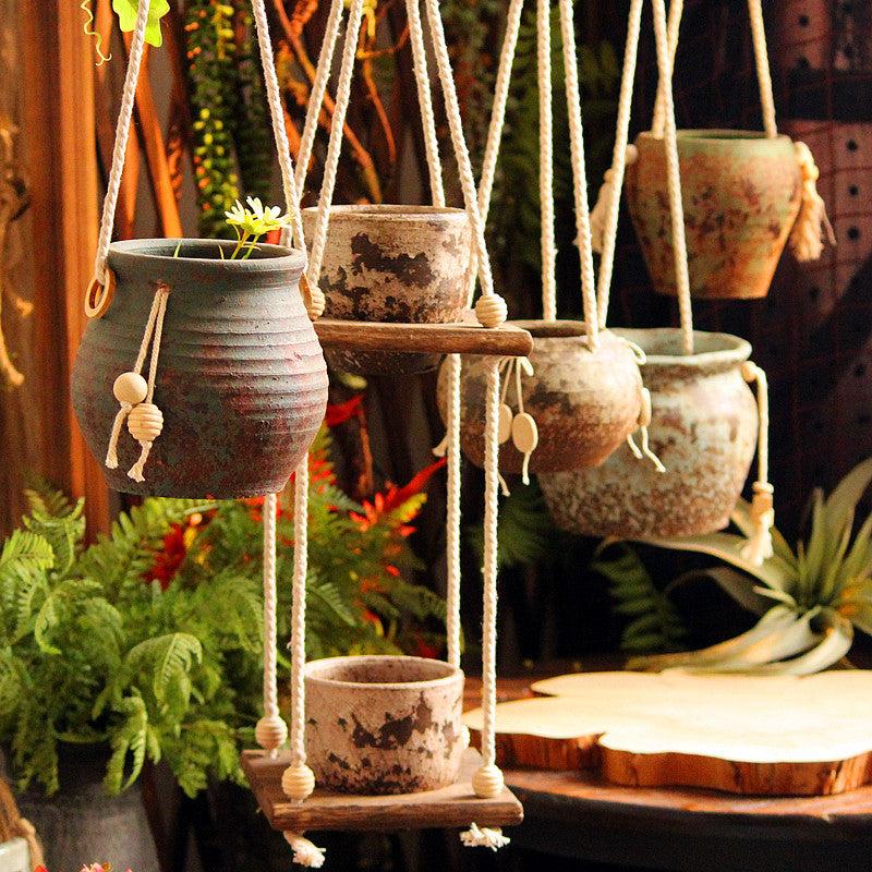 Rustic hanging stoneware flower pots with hemp rope in a retro nostalgic style, ideal for indoor use.
