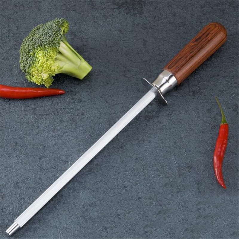 Household kitchen knife sharpener with color wood handle and carbon steel rod on countertop with vegetables.