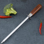 Household kitchen knife sharpener with color wood handle and carbon steel rod on countertop with vegetables.