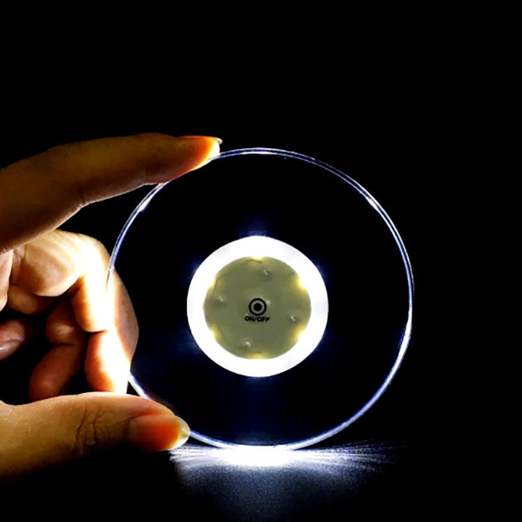 Round transparent acrylic LED coaster glowing in the dark.